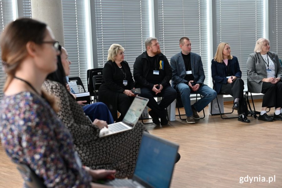 Kobiety i mężczyźni siedzący na krzesłach w sali konferencyjnej
