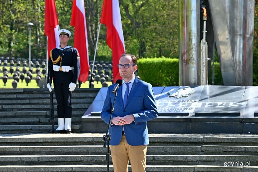 Jakub Ubych - wiceprzewodniczący Rady Miasta Gdyni przemawiający podczas uroczystości z okazji 78. rocznicy zakończenia II wojny światowej, które odbyły się na Cmentarzu Wojennym w Redłowie. W tle posterunek honorowy i fragment pomnika Obrońców Wybrzeża // fot. Magdalena Czernek