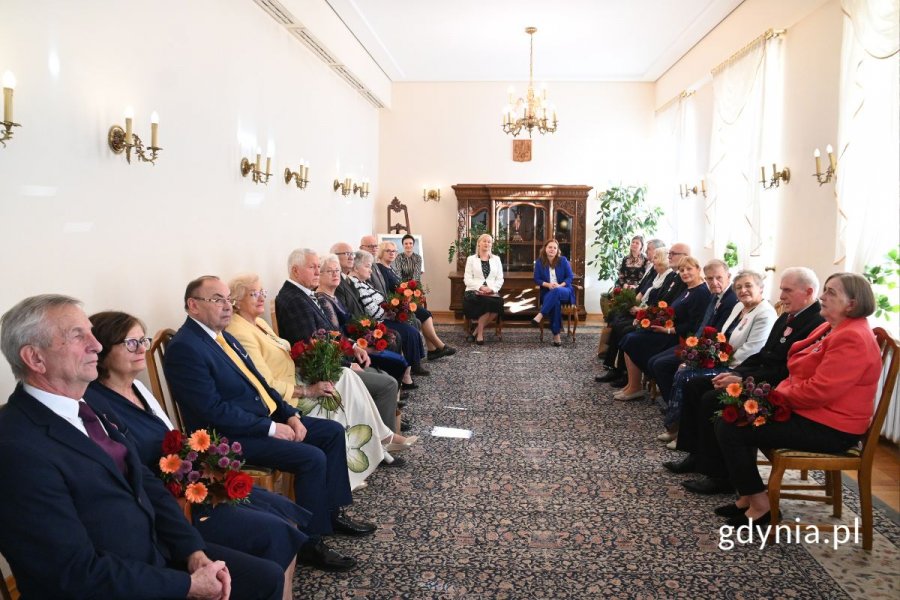 Seniorzy siedzący na krzesłach w eleganckiej sali
