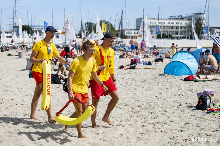 Trzech ratowników idzie plażą.