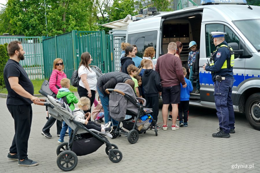 Uczestnicy festynu zaglądający do wnętrza radiowozu policyjnego 