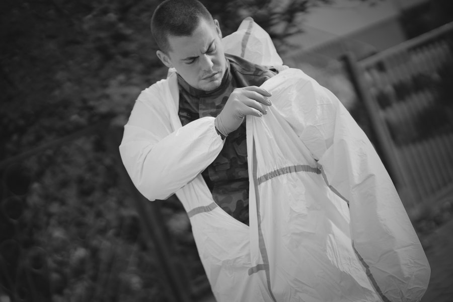 Żołnierz zakłada na mundur biały kombinezon ochronny // fot.  st. chor. szt. mar. Piotr Leoniak