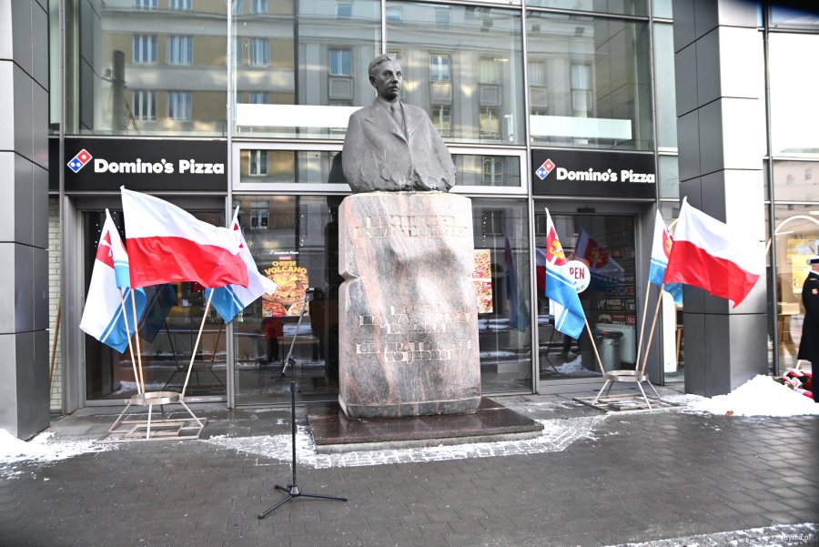 Pomnik, obok flagi kraju i miasta