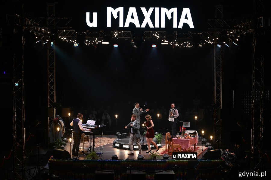 Hala Polsat Plus Arena Gdynia, scena, aktorzy na scenie, napisy "U Maxima", muzycy na scenie, ciemność w tle