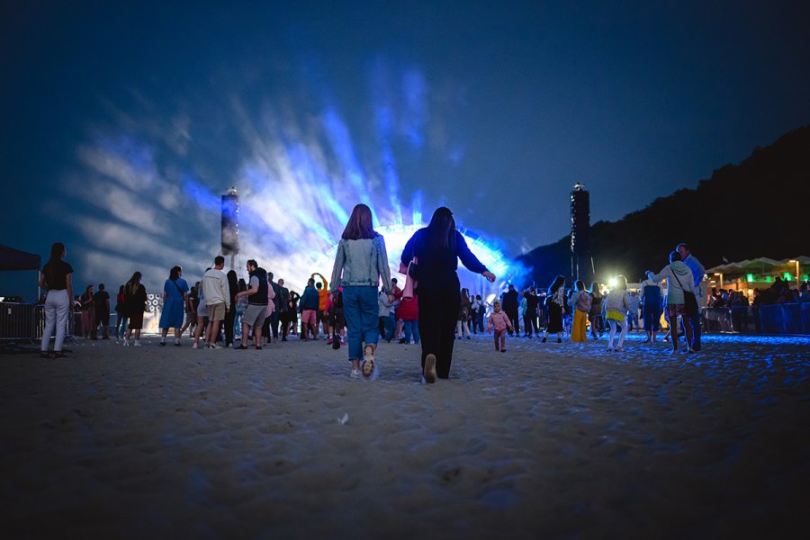 Ludzie bawią się na plaży podczas koncertu.