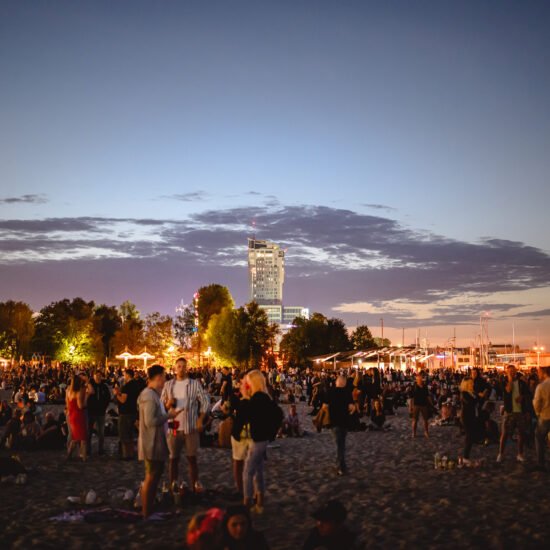 Festiwal Cudawianki. Ujęcie plaży po zachodzie słońca, tłum ludzi i scena, festiwal muzyczny