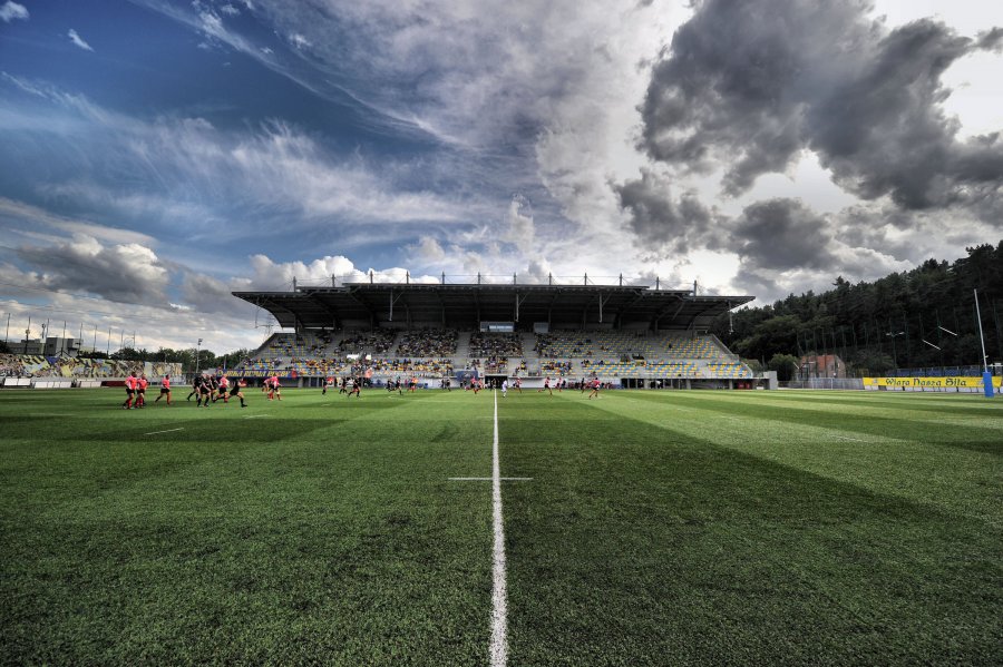 Narodowy Stadion Rugby, ujęcie z murawy. Widoczne są boisko, trybuna oraz lekko zachmurzone niebo.