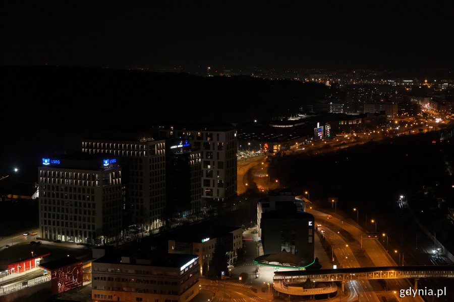 Nocne zdjęcie budynków, w których są zgaszone światła, stojących przy oświetlonych ulicach