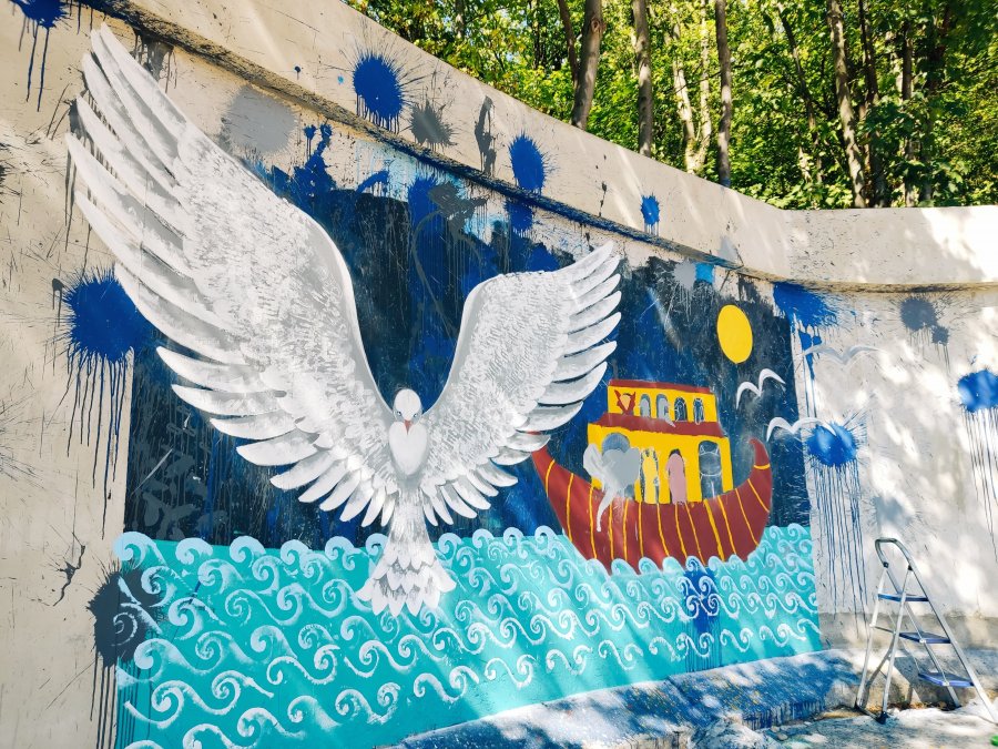 Mural na Śmidowicza. Na pierwszym planie gołąb z szeroko rozpostartymi skrzydłami na, na drugim arka ze zwierzętami unosząca się na falach