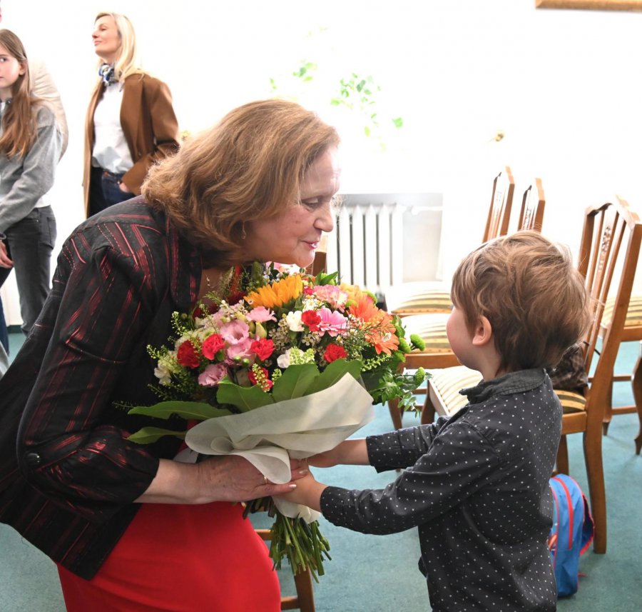 Mały chłopiec wręcza starszej pani bukiet kwiat&oacute;w