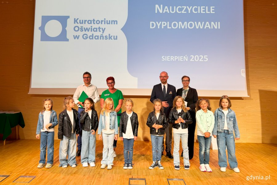Osoby na scenie pozujące do zdjęcia po wręczeniu nominacji