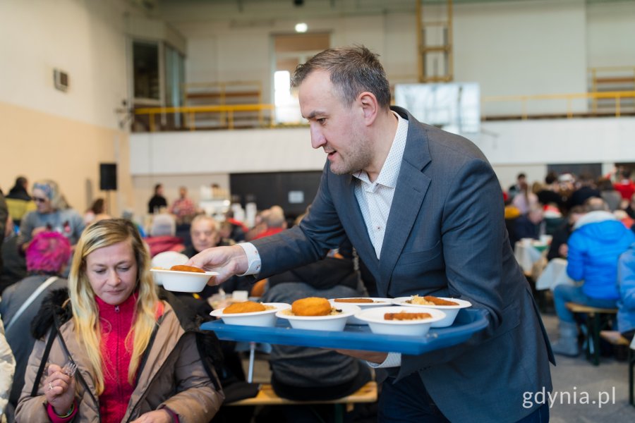 zWiceprezydent Tomasz Augustyniak roznoszący świąteczne potrawy gościom wigilii dla samotnych i potrzebujących 
