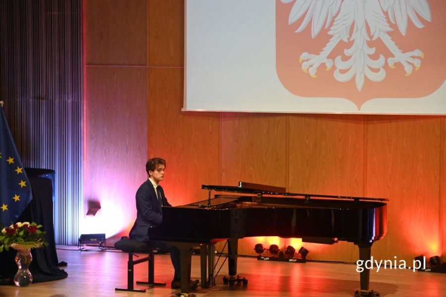 Elegancko ubrany mężczyzna grający na czarnym fortepianie