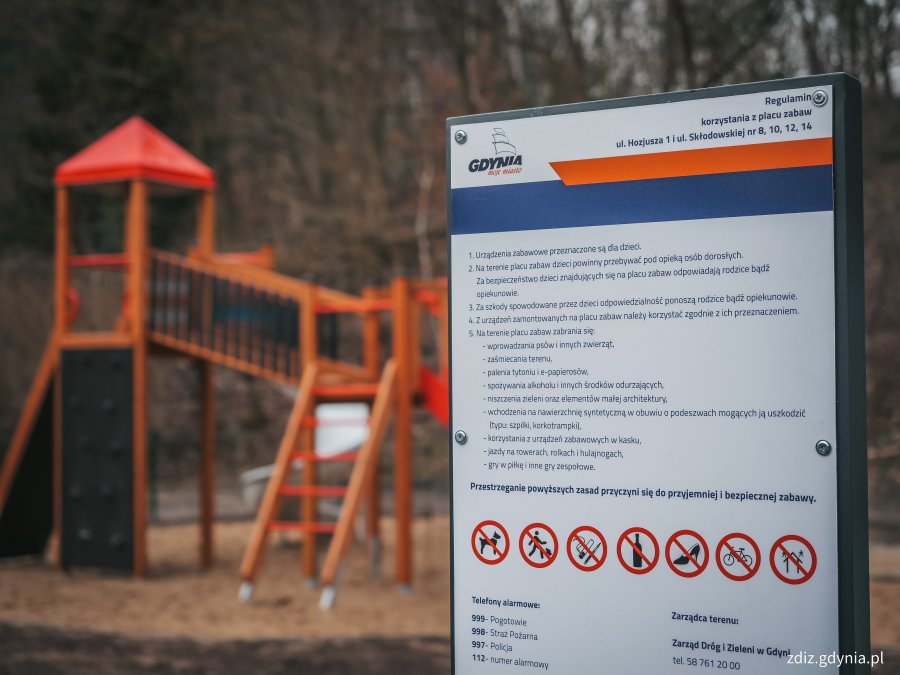 tablica z regulaminem placu zabaw, w tle urządzenia zabawowe