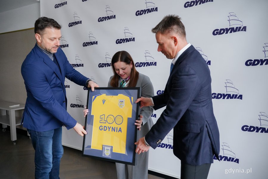 Wojciech Pertkiewicz &ndash; prezes zarządu Arki Gdynia oraz Marcin Gruchała &ndash; większościowy akcjonariusz klubu przekazujący pamiątkową koszulkę z okazji stulecia Gdyni na ręce prezydent Aleksandry Kosiorek 