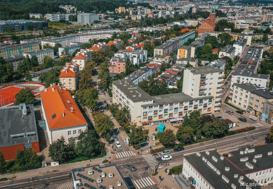 widok z góry na ulicę, w tle ruch uliczny, budynki i zieleń, widok z góry na miasto