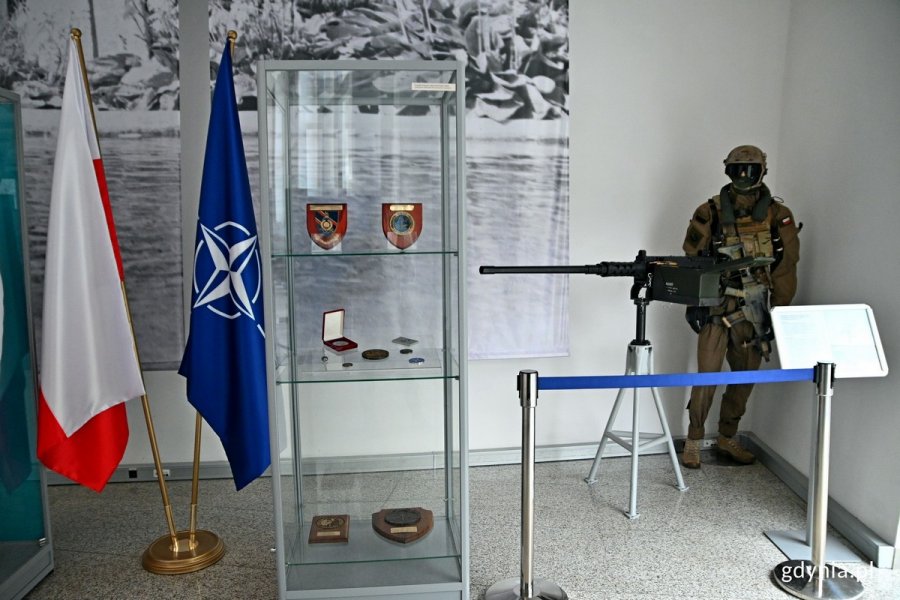 Fragment wystawy „25 lat Polski w NATO” w Muzeum Marynarki Wojennej. Po lewej flagi Polski i NATO, w środku - gablota z eksponatami, po prawej - mundur żołnierza