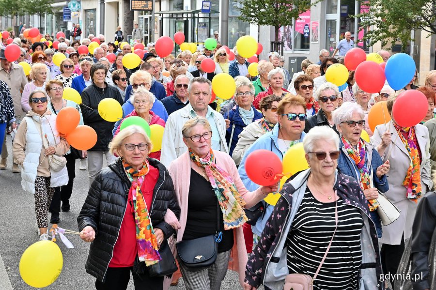 Uczestnicy przemarszu w ramach V Pomorskiego Dnia Seniora idący ul. Świętojańską. W kolorowych strojach i z balonami w rękach
