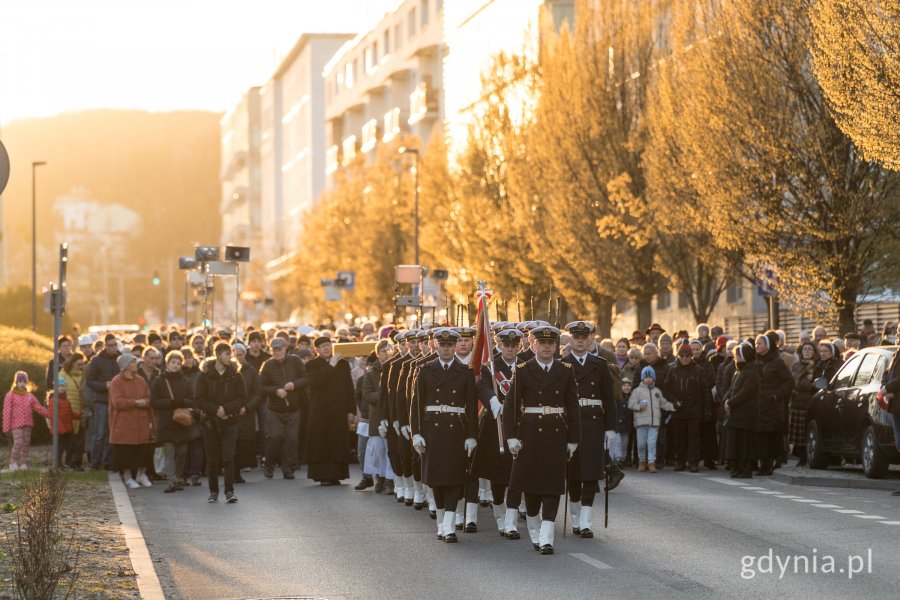 Uczestnicy Gdyńskiej Drogi Krzyżowej idący al. Marsz. Piłsudskiego na tle zachodzącego słońca