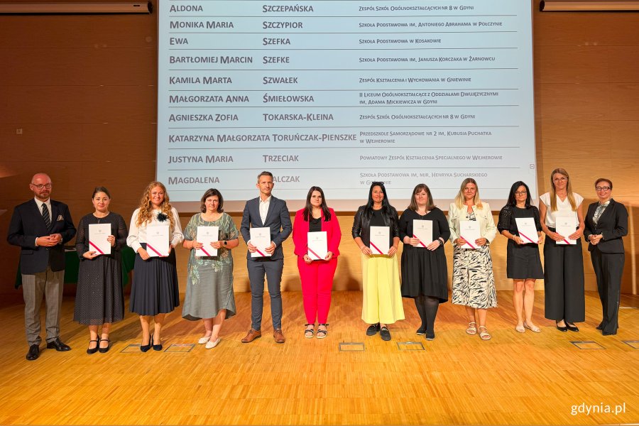 Osoby na scenie pozujące do zdjęcia po wręczeniu nominacji