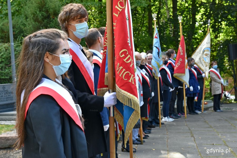 Gdyńscy uczniowie i przedstawiciele stowarzyszeń na uroczystości 80. rocznicy zbrodni katyńskiej. Przez ramiona mają przewieszone biało-czerwone szarfy. Niektórzy trzymają w rękach sztandary // fot. Magdalena Czernek
