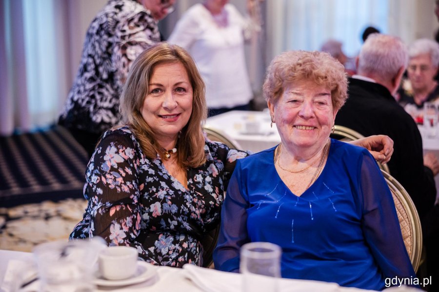 Dwie panie pozują do zdjęcia przy stole