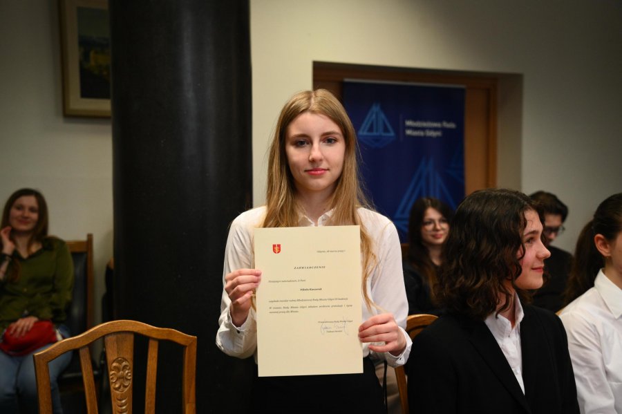 Nastolatka w białej bluzce z dyplomem