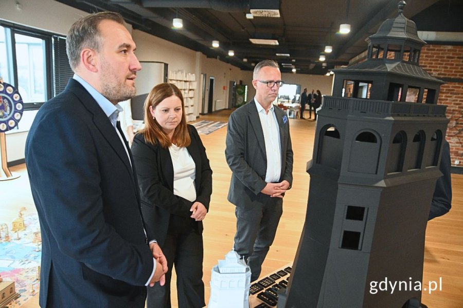 Grupa osób przyglądająca się makiecie budynku