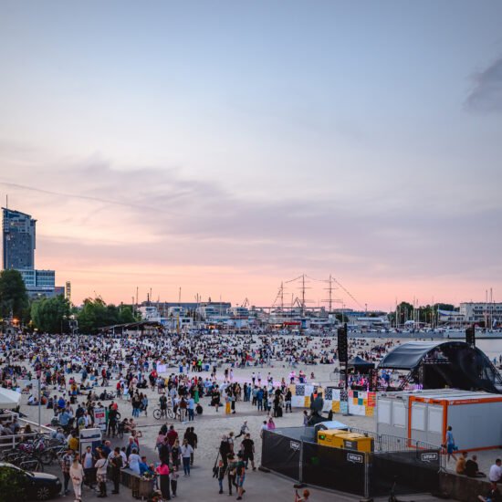 Festiwal Cudawianki. Ujęcie plaży po zachodzie słońca, tłum ludzi i scena, festiwal muzyczny