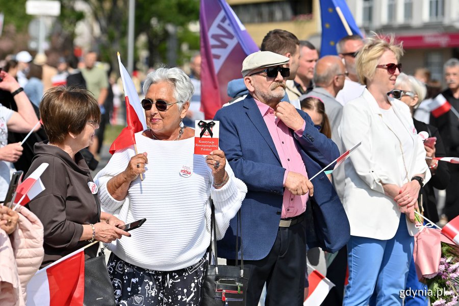 Mieszkańcy z biało-czerwonymi chorągiewkami na skwerze Kościuszki