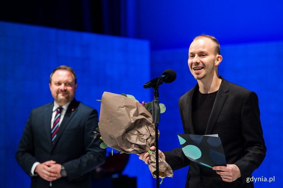 Filip Wójcik, aktor Teatru Gdynia Główna, z nagrodą z okazji Międzynarodowego Dnia Teatru. Na scenie w towarzystwie wiceprezydenta Gdyni Marka Łucyka // fot. Karol Stańczak