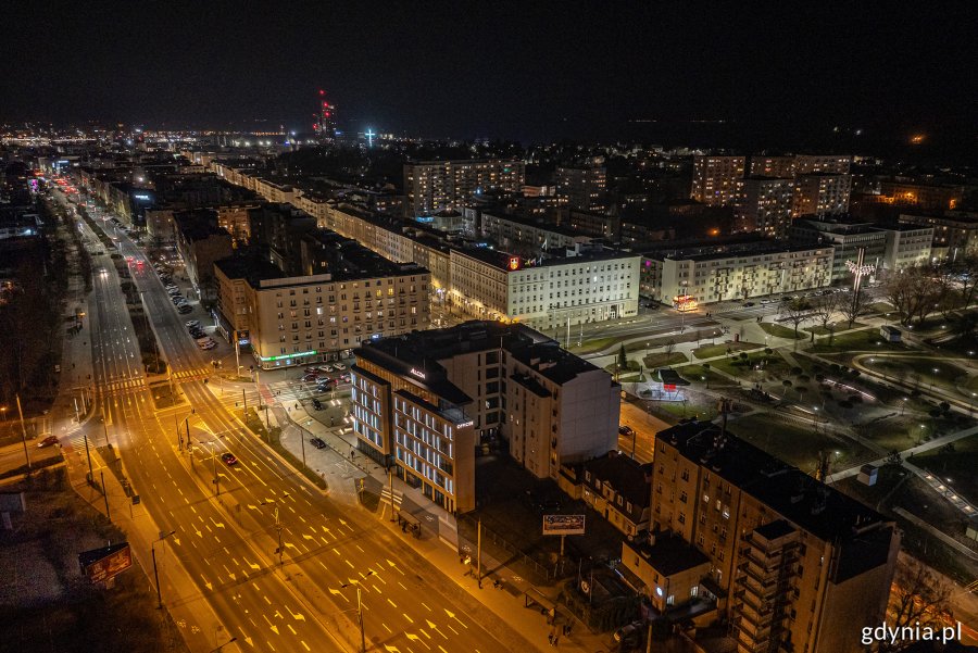 Nocne zdjęcie budynków, w których są zgaszone światła, stojących przy oświetlonych ulicach