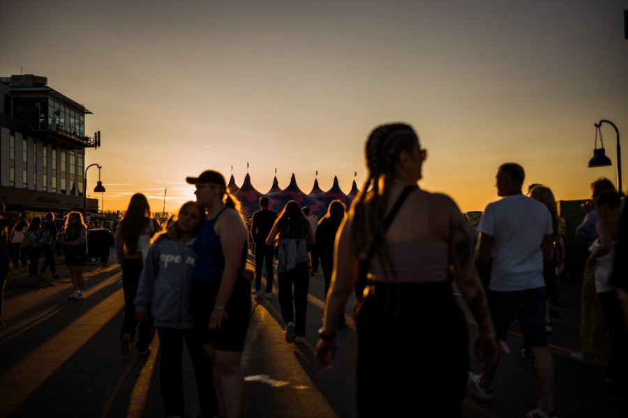 Uczestnicy Open'era spacerujacy po miasteczku festiwalowym w promieniach zachodzącego słońca // fot. Krzysztof Szlęzak
