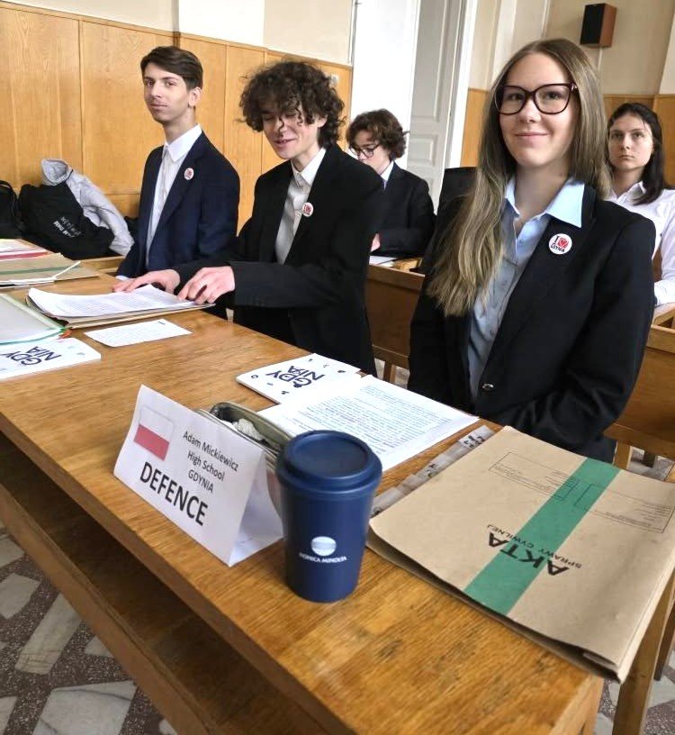 Młodzi ludzie w za stolikiem, na pierwszym planie akta