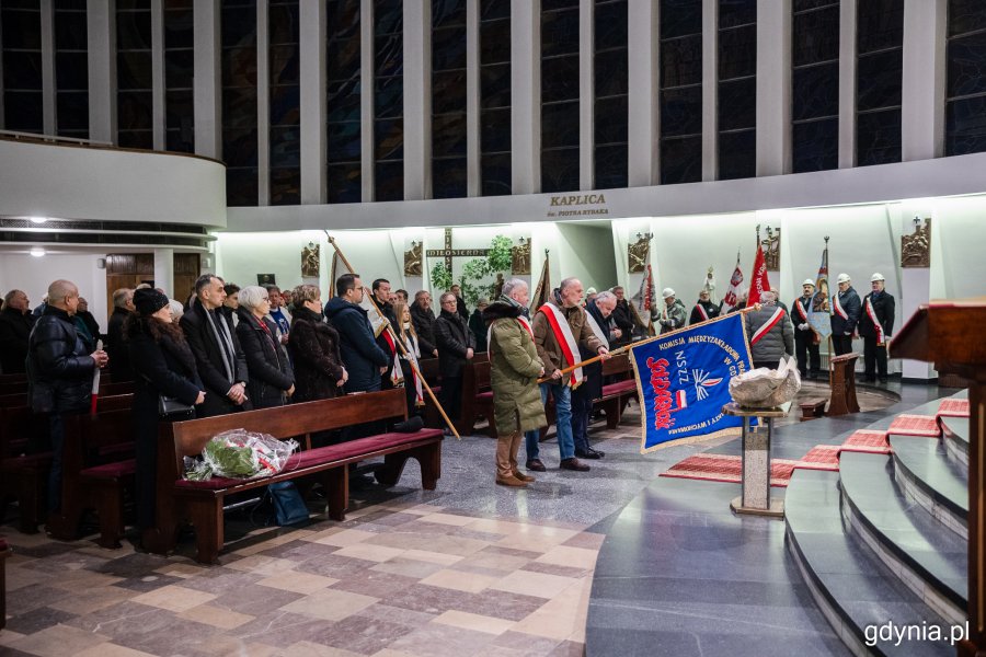 Mężczyźni stojący w kościele i pochylający sztandar w kierunku ołtarza