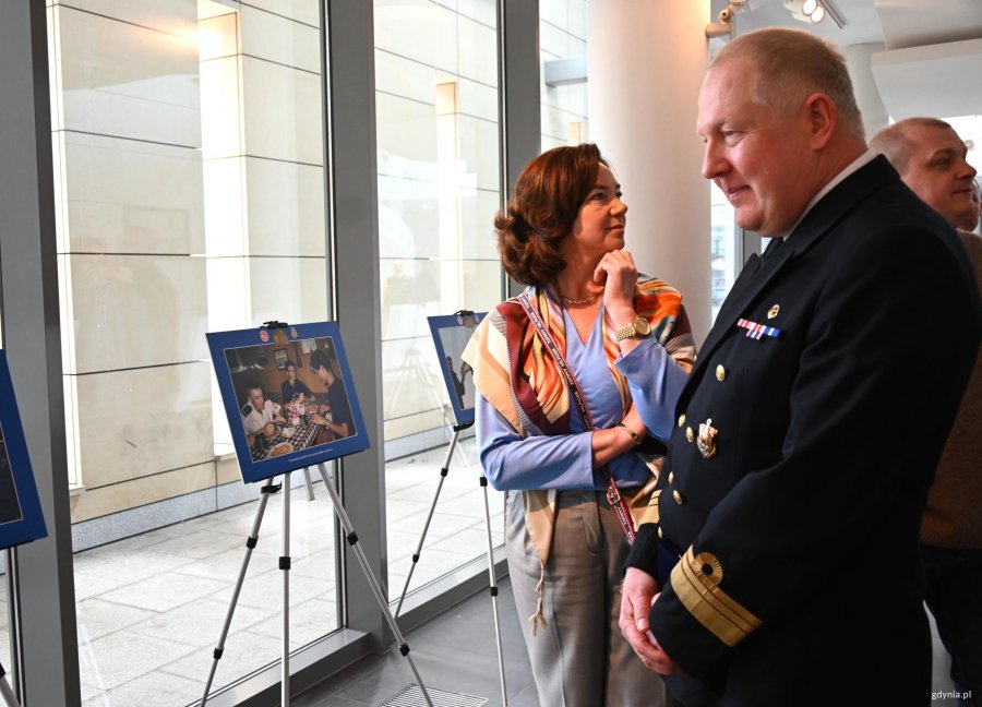 Mężczyzna w mundurze przy fotografii, w tle kobieta