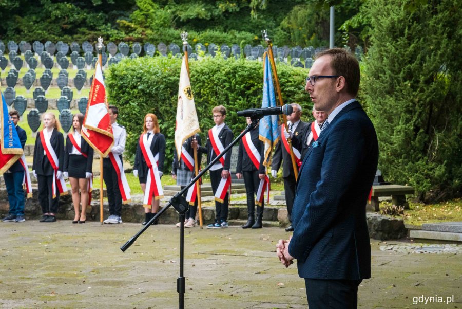 Podczas uroczystości głos zabrał Jakub Ubych, wiceprzewodniczący Rady Miasta Gdyni. W tle: poczty sztandarowe z gdyńskich szkół // fot. Kamil Złoch