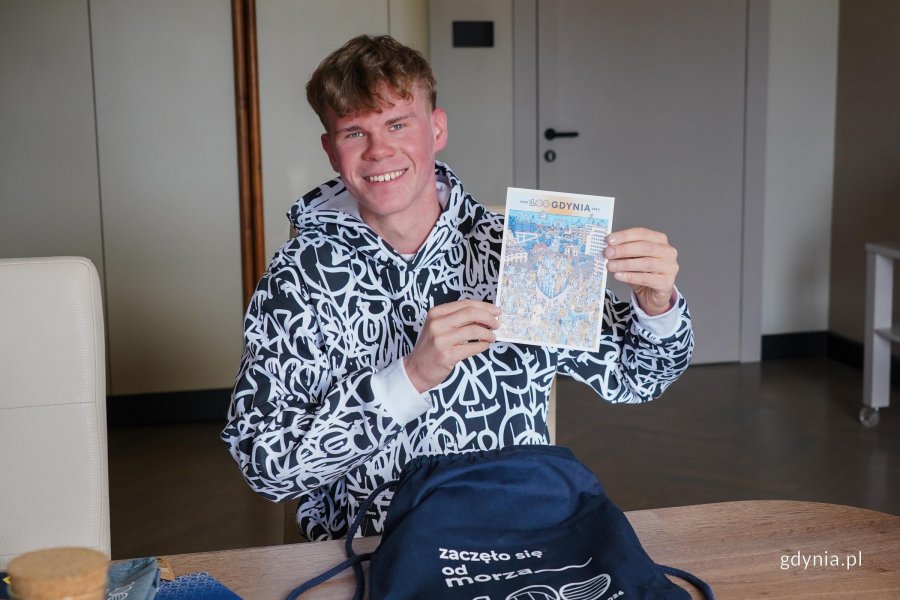 Dominik Kaleta, mieszkaniec Chwarzna-Wiczlina, z kartką z motywem plakatu Jana Rutki na stulecie Gdyni 