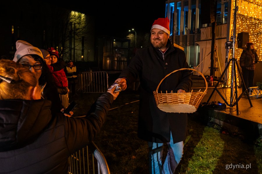 Radny Łukasz Strzałkowski rozdający słodycze dla mieszkańców. Gdyńskie mikołajki w muszli koncertowej na placu Grunwaldzkim (fot. Kamil Złoch)