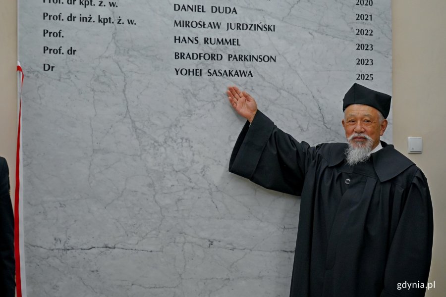 dr Yohei Sasakawa, doktor honoris causa Uniwersytetu Morskiego, wskazujący swoje nazwisko na tablicy pamiątkowej