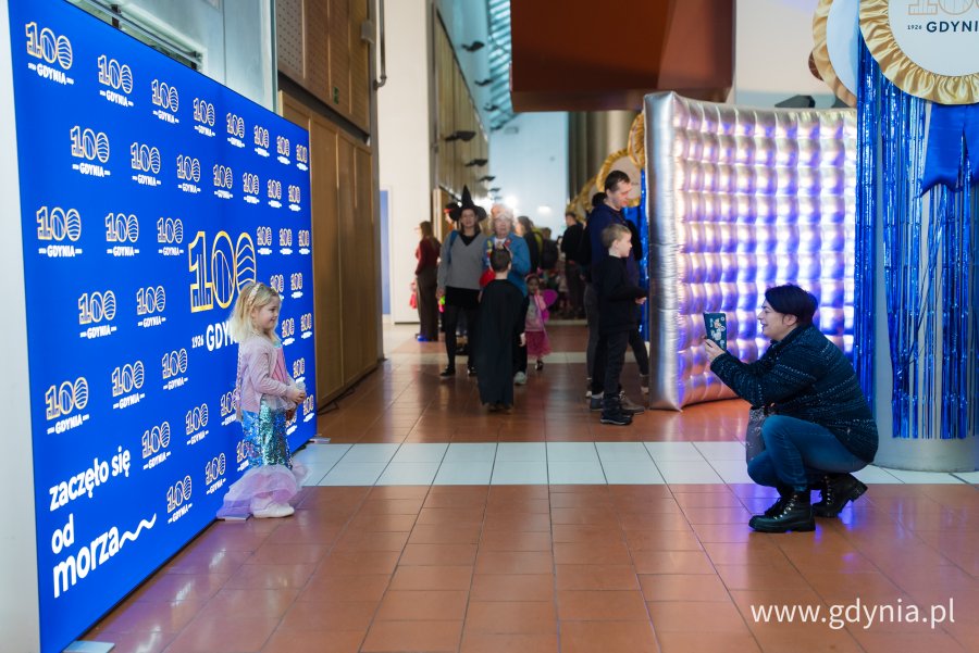Dziewczynka pozuje do zdjęcia z napisem Gdynia 100