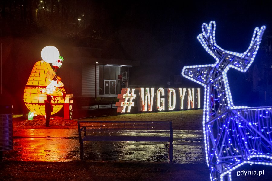Iluminacje na placu Grunwaldzkim. Po lewej stronie widoczny jest świecący św. Mikołaj oraz napis "#wGdyni". Po prawej stronie znajduje się świecący na niebiesko renifer. // fot. Przemysław Kozłowski