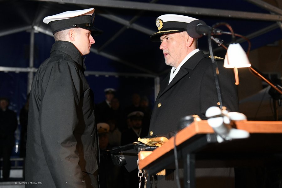 Rektor Akademii Marynarki Wojennej wręcza odznaczenie studentowi w mundurze.
