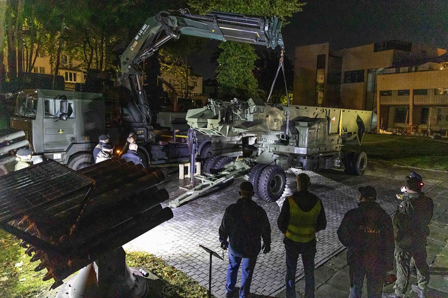 Żołnierze rozładowują wyrzutnie rakiet z samochodu ciężarowego.