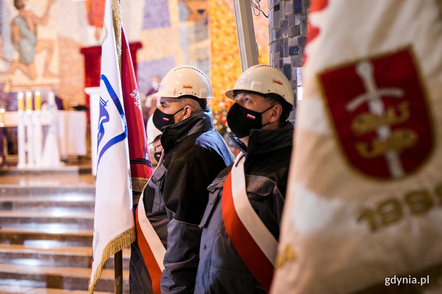 Stoczniowcy w białych kaskach ze znakiem Solidarności i sztandarami podczas mszy świętej w 50. rocznicę wydarzeń Grudnia '70 // fot. Karol Stańczak