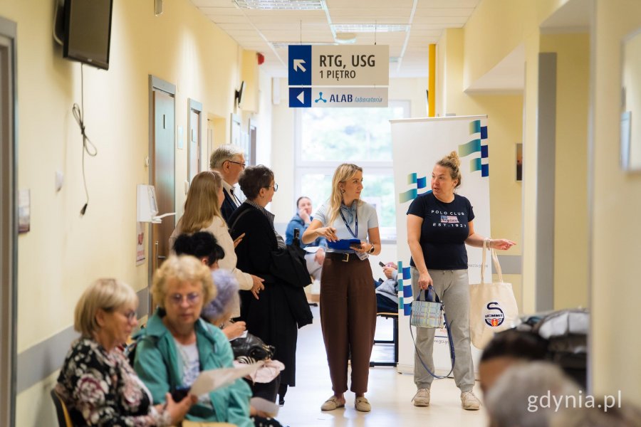 Pracownice udzielają informacji uczestnikom akcji profilaktycznej w korytarzu plac&oacute;wki medycznej