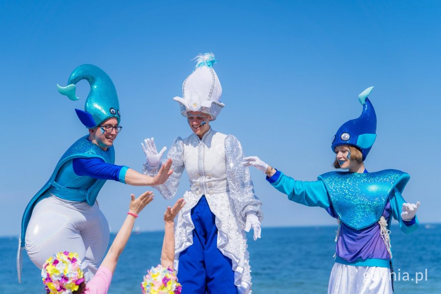 Artyści na szczudłach na tle morza