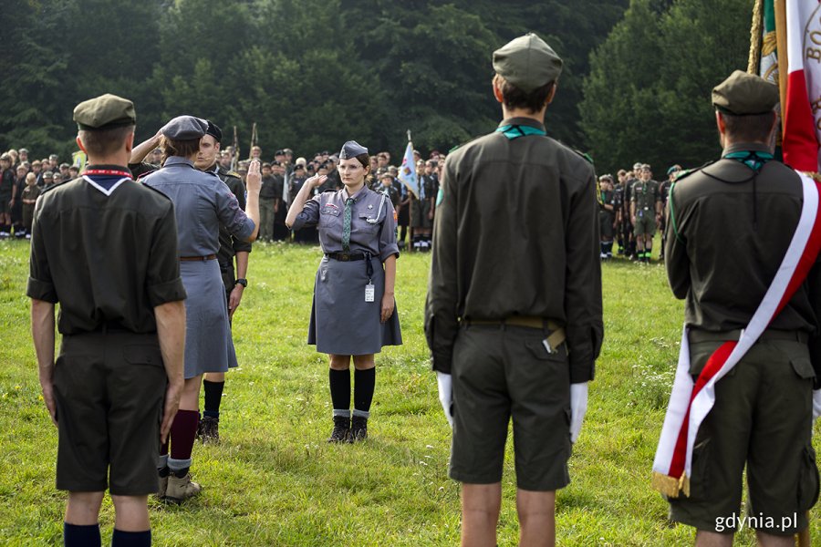 Harcerka składa meldunek na apelu i salutuje.