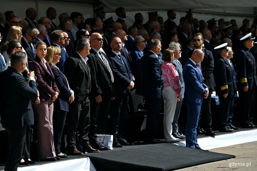 Uczestnicy uroczystości chrztu okrętu  ORP &bdquo;Wicher&rdquo; zgromadzeni przy jednym z nabrzeży PGZ Stoczni Wojennej. Wśr&oacute;d nich radna Gdyni Anna Salomon 