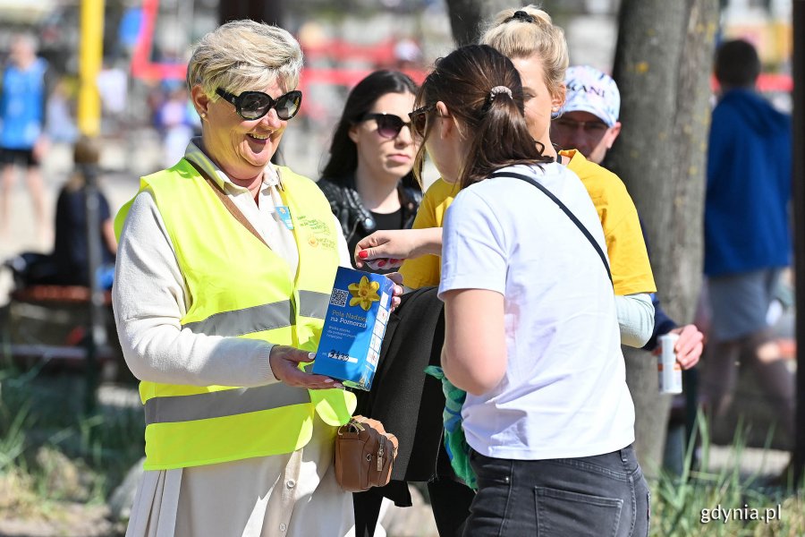 Kwestująca radna Elżbieta Raczyńska i darczyńcy wrzucający datki do puszki